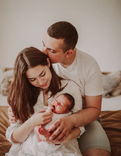 Rodinná fotografie focení ve stylu Lifestyle fotografování fotografkou z Fotky s duší, kde se rodiče dívají na miminko a sedí na posteli.